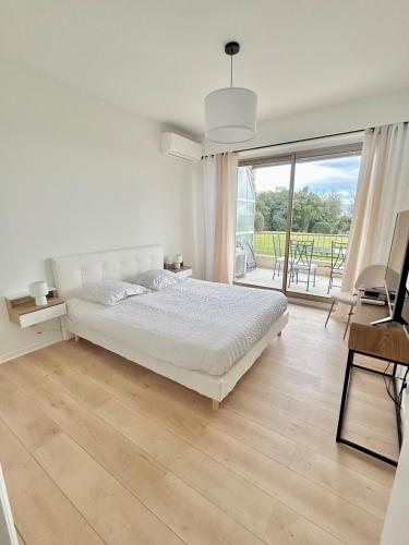 une chambre blanche avec un lit et une grande fenêtre dans l'établissement Le Grand Soleil, à Nice