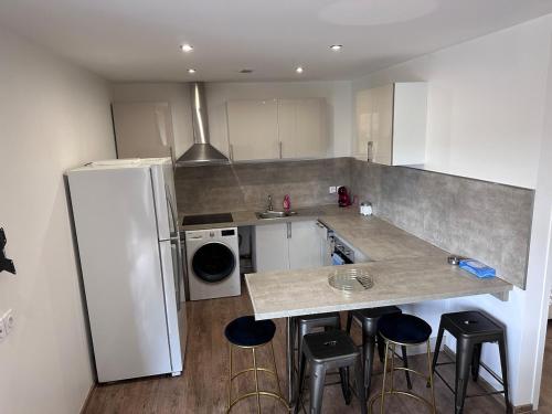 La cuisine est équipée d'un réfrigérateur blanc et de tabourets de bar. dans l'établissement Apparemment calme proche Aix-les-Bains, à Sonnaz