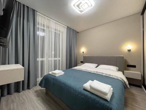 a bedroom with a blue bed and a window at Uzhhorod Apartment Lux in Uzhhorod