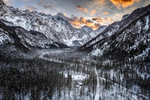 a snowy mountain range with a lake in the foreground at Eko hiša-Eco House Na razpotju in Solčava