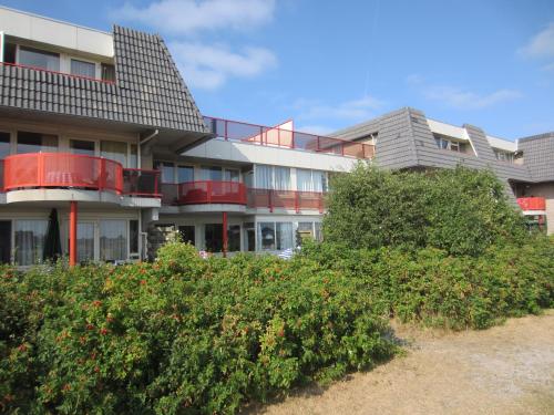 een appartementencomplex met rode balkons en struiken bij Duinzicht in Buren