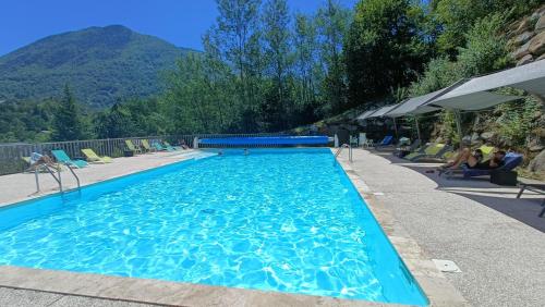 une grande piscine bleue avec des montagnes en arrière-plan dans l'établissement L'APPARTEMENT DE NOAH appartement Rez de chaussée classé 2 étoiles avec terrasse, à Ax-les-Thermes