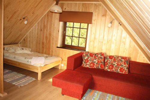 a room with a red couch and a bed and a window at Atpūtas komplekss " Ezerkrasti" in Čornaja