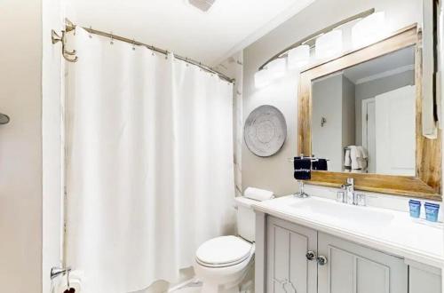 a bathroom with a toilet and a sink and a mirror at Pineapple Palms at the Sea Cabins in Isle of Palms