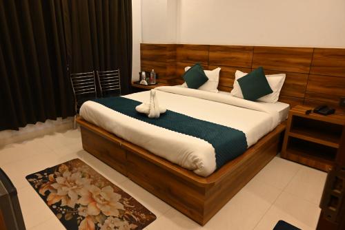 a bedroom with a large bed with green and white pillows at Hotel Vaidik Ganga in Rishīkesh