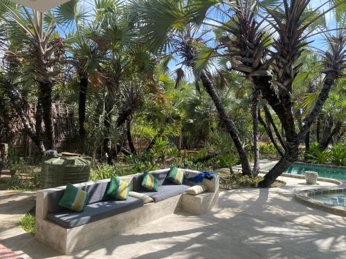 a couch sitting next to a pool with palm trees at Sandy Feet Retreat in Malindi