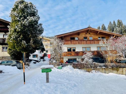 a snow covered house with a sign in front of it at Zirmweg Appartements in Oberau