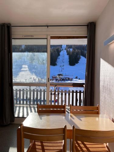 une table et des chaises dans une pièce avec une grande fenêtre dans l'établissement tranquilité montagnarde, à Saint-Étienne-en-Dévoluy
