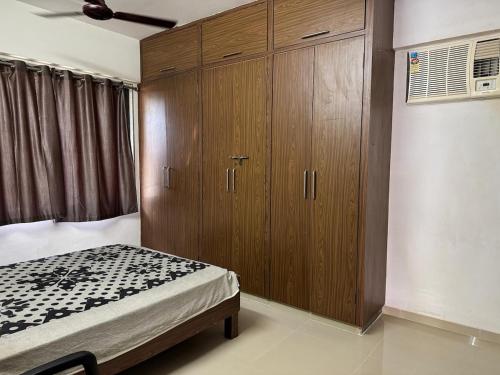 a bedroom with a bed and a large wooden cabinet at New Luxurious and spacious 2bhk flat in Tirupati near alipiri for upto 20 people in Tirupati