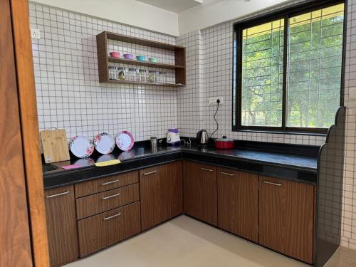 a kitchen with brown cabinets and a window at New Luxurious and spacious 2bhk flat in Tirupati near alipiri for upto 20 people in Tirupati