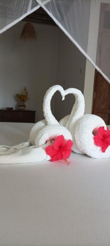 two towels shaped like swans sitting on a bed at Amka Guest house in Jambiani