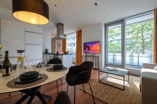 ein Wohnzimmer mit Tisch und Stühlen und eine Küche in der Unterkunft Come2Stay Hafencity - Marco Polo Tower 2 in Hamburg