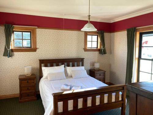 a bedroom with a bed and two windows at Fantail Cottage in Hurunui