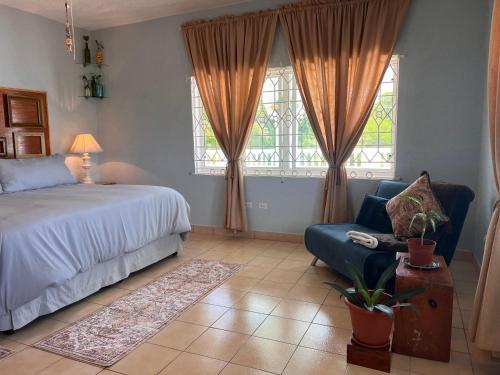 a bedroom with a bed and a chair and windows at 428 Boutique Guesthouse in Boscobel