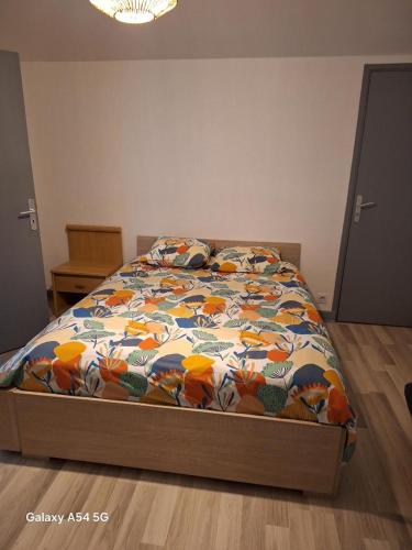 a bed with a colorful comforter in a bedroom at Cocon in Domérat