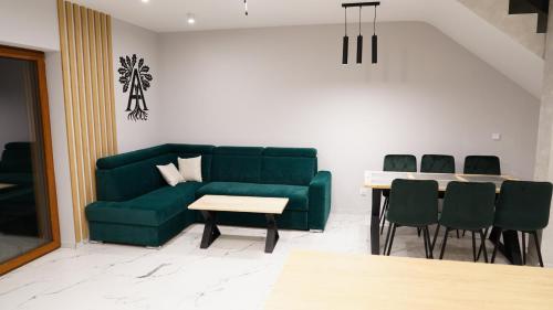 a living room with a green couch and a table at Apartamenty pod Dębami - noclegi Beskid Niski in Odrzechowa