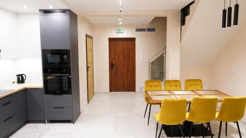 a kitchen and dining room with a wooden table and yellow chairs at Apartamenty pod Dębami - noclegi Beskid Niski in Odrzechowa