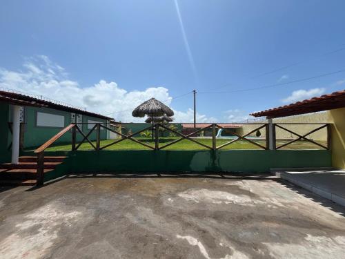 eine Terrasse mit einem grünen Zaun und einem Sonnenschirm in der Unterkunft Casa de praia in São José de Ribamar