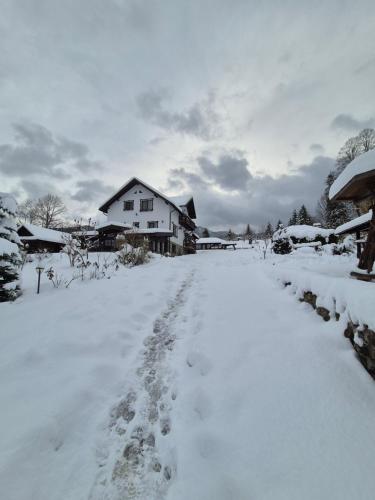 a snow covered road with footprints in front of a house at Casa Izvorul Rarăului in Câmpulung Moldovenesc