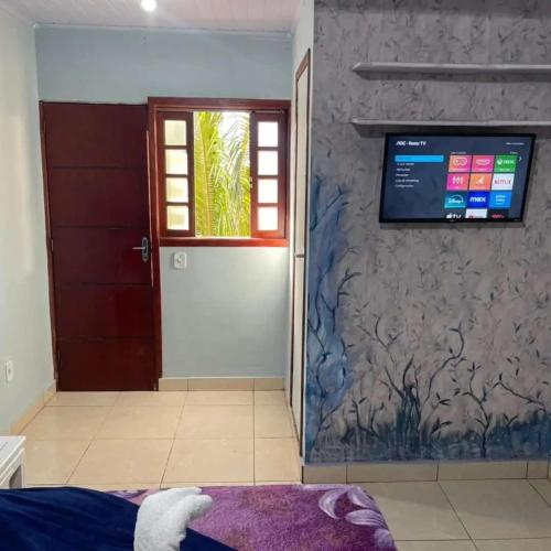 a room with a door and a television on a wall at Hospedagem Por do sol in Arraial do Cabo