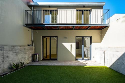 a house with a balcony and a green lawn at Varandas do Porto Coliving in Porto