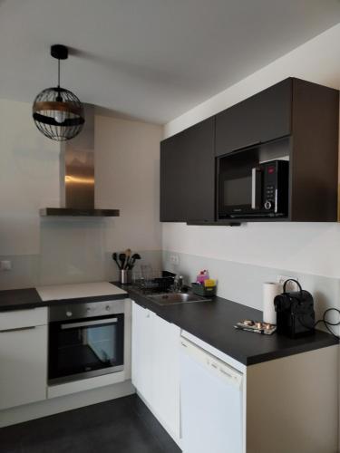 une cuisine avec des armoires blanches et des appareils noirs dans l'établissement Résidence prémium MontBlanc, à Sallanches