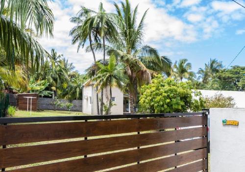 a wooden fence with palm trees in the background at Maison cosy en bord de mer-wifi et parking gratuit in Saint-Joseph