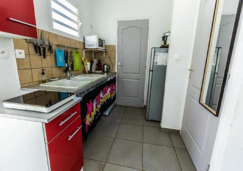 a small kitchen with a sink and a refrigerator at Maison cosy en bord de mer-wifi et parking gratuit in Saint-Joseph