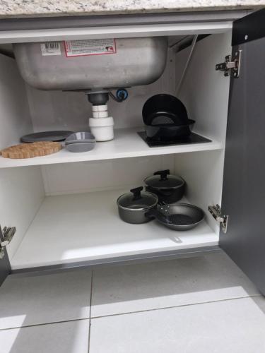 a kitchen shelf with pots and pans and a sink at Apartamento 1 quarto Edifício Ipanema Residence in Campos dos Goytacazes