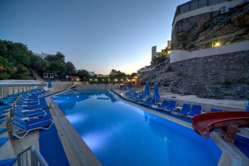 a swimming pool with blue chairs and a building at Crystal Hotel Bodrum in Gumusluk