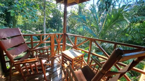 a porch with two chairs and a table at Cabinas Costa Tropicana in Uvita