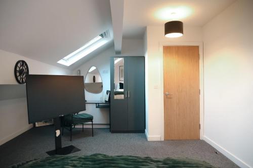 a room with a hallway with a door and a television at City Centre Retreat Walk To Shops & Dining, Contractors Welcome in Bradford