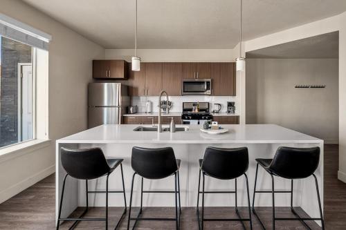 a kitchen with a large white island with black chairs at Gorgeous 2BD 2BA Pool,Gym,Htub near Convention Ctr in Salt Lake City
