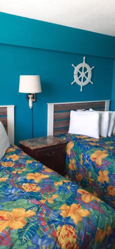 a bedroom with two beds and a blue wall at Daytona Beach Hawaiian Inn in Daytona Beach