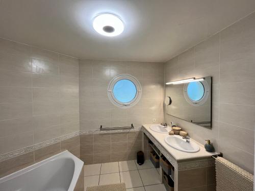 une salle de bain avec deux lavabos, une baignoire et un miroir dans l'établissement LA VILLA DES PINS, à Lacanau-Océan