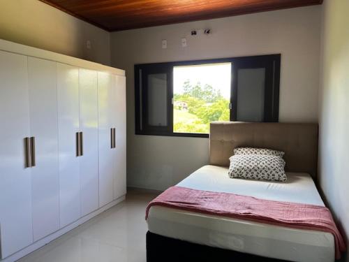 a bedroom with a large bed and a window at Pousada Caminho da Serra in Louro Müller