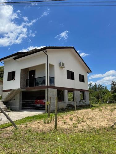 a white house with a car parked in front of it at Pousada Caminho da Serra in Louro Müller