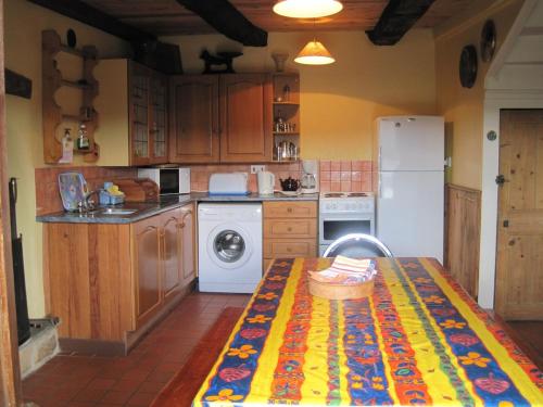 une cuisine avec une table et un réfrigérateur blanc dans l'établissement Rest Huella Farmhouse, à Saint-Ségal
