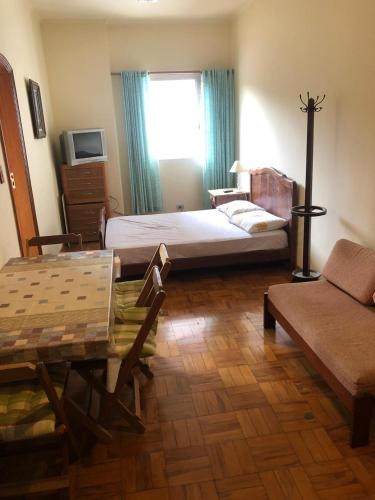 ein Schlafzimmer mit einem Bett und einem Tisch und einem Fenster in der Unterkunft Condomínio Quisisana in Poços de Caldas