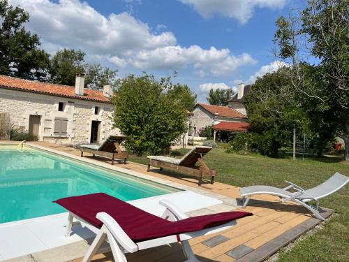 a swimming pool with two lounge chairs next to a house at Maison Périgord vert piscine et spa in La Roche-Chalais
