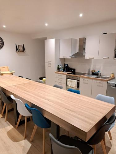uma cozinha com uma grande mesa de madeira e cadeiras em Gite Ardennais 18 personnes "les gronchons" em Haybes