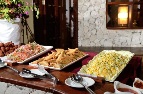 a table topped with trays of different types of food at Kena Beach Hotel in Matemwe