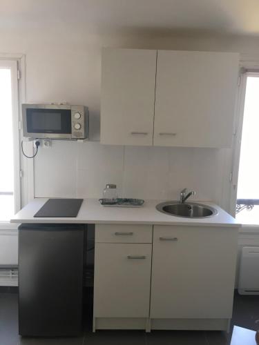 une cuisine blanche avec un évier et un micro-ondes dans l'établissement Studio Centre, Proche du Vieux Port de Marseille, à Marseille