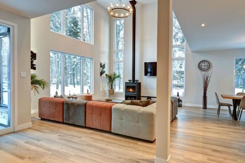 a living room with a large couch and windows at Modern Luxury 4-Bedroom Home by Mont-Tremblant Ski Resort in Lac-Superieur