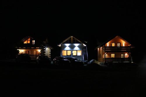 two houses with lights on them at night at Casutele dintre brazi in Coverca