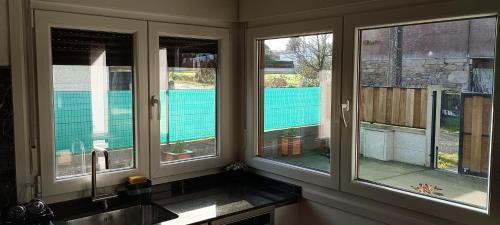 a kitchen with three windows and a sink at Casa da Braña in Teo