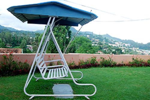 a chair sitting in the grass under an umbrella at Bella Vista Homestay in Coonoor