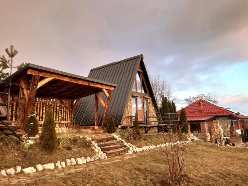a wooden house with a gambrel roof at Razele Trascaului in Rîmeţi