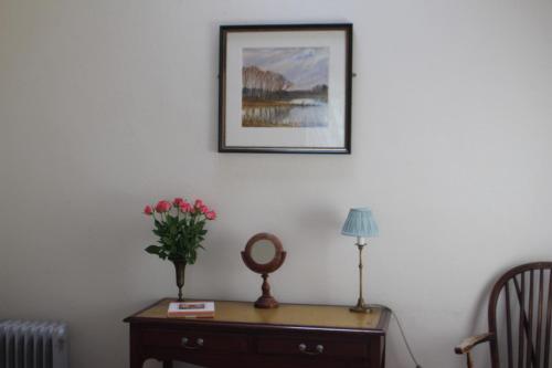 a vase of flowers on a table with a picture on the wall at The Pump House in Athy