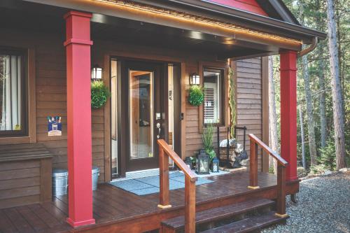 a front porch of a house with red columns at Villa Experience Nature Le Nid in Saint-Irénée